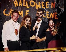 staand tegen misdrijf tafereel muur. vrienden is Aan de thematisch halloween partij in eng bedenken en kostuums foto