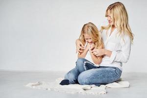 moeder met haar dochter samen is Aan de grond in de studio met wit achtergrond foto