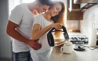 jong paar Bij ochtend- samen staand Aan de modern keuken foto