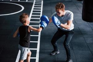 jong trainer geeft les kind boksen sport in de Sportschool foto