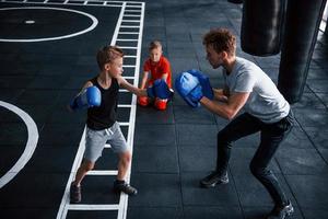 jong trainer geeft les kinderen boksen sport in de Sportschool foto