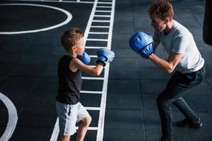 jong trainer geeft les kind boksen sport in de Sportschool foto