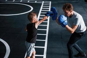 jong trainer geeft les kind boksen sport in de Sportschool foto