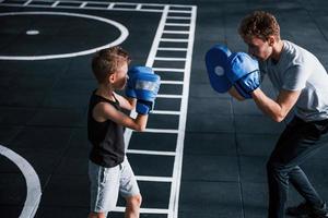 jong trainer geeft les kind boksen sport in de Sportschool foto