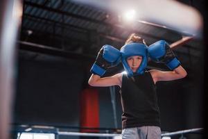 jongen in sportief beschermend uitrusting staand Aan de boksen ring en vieren zege foto