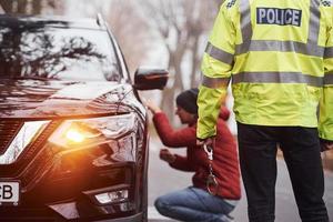 Politie officier in groen uniform gevangen auto- diefstal Aan de weg foto