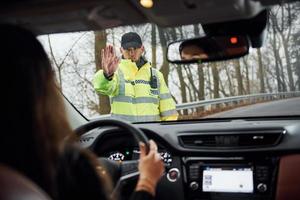 mannetje Politie officier in groen uniform stopt voertuig met vrouw bestuurder Aan de weg foto