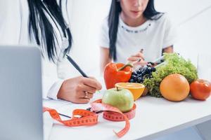 vrouw voedingsdeskundige geeft overleg naar geduldig binnenshuis in de kantoor foto