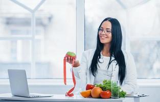 vrouw voedingsdeskundige in wit jas Holding appel met meten plakband foto