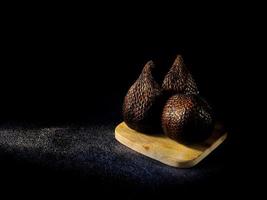 salak is een type van palm fruit algemeen gegeten. slang fruit, haar wetenschappelijk naam is salacca zalacca. zwart zand achtergrond. foto