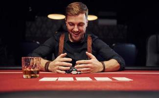 gelukkig elegant jong Mens zit in casino en vieren zijn zege in poker spel foto