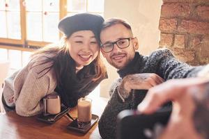 multiraciaal paar maken selfie in cafe. Aziatisch meisje met haar Kaukasisch vriendje foto