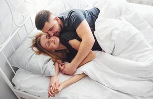 schattig jong paar aan het liegen naar beneden Aan de bed en slapen samen foto