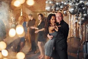 jong paar dansen tegen hun vrienden in Kerstmis versierd kamer en vieren nieuw jaar foto