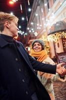 paar hebben een wandelen samen Aan de Kerstmis versierd straat foto