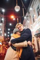 gelukkig jong paar in warm kleren is Aan Kerstmis versierd straat samen foto