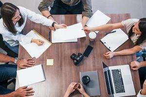 top visie van jong bedrijf mensen dat werken samen met documenten en laptop in de modern kantoor foto