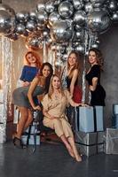 jong Dames in feestelijk kleren vieren nieuw jaar binnenshuis van Kerstmis versierd kamer samen foto