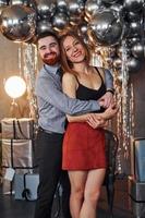 paar is in Kerstmis versierd kamer samen. vieren nieuw jaar foto
