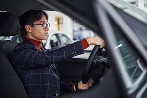 Mens in eyewear en formeel kleren zittend binnen van modern auto foto