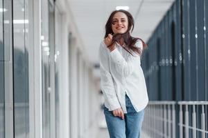 brunette in wit overhemd binnenshuis in modern luchthaven of gang Bij dag foto