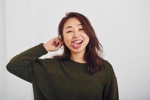 portret van gelukkig Aziatisch jong meisje dat staand binnenshuis in de studio tegen wit achtergrond foto