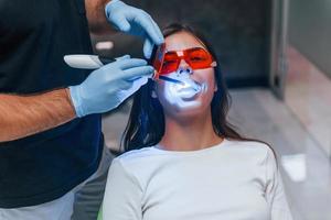 mooi vrouw in rood beschermend bril hebben een bezoek in de tandarts kliniek. opvatting van stomatologie foto