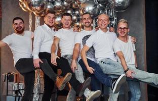 groep van vrolijk mannen staand samen in Kerstmis versierd kamer en poseren voor een camera foto