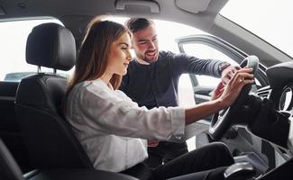 vrouw testen auto door helpen van mannetje assistent binnenshuis in de salon foto