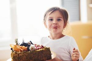 vrolijk weinig meisje aan het eten vers diëtisch taart Aan de keuken foto