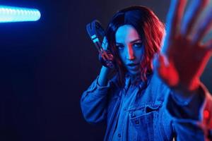 portret van jong meisje dat luisteren naar muziek- in hoofdtelefoons in rood en blauw neon in studio foto