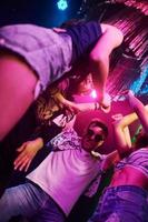 visie van hieronder van jong mensen dat hebben pret in nacht club met kleurrijk laser lichten foto