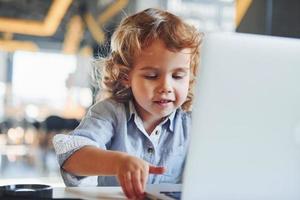 slim kind in gewoontjes kleren gebruik makend van laptop voor onderwijs doeleinden of pret foto