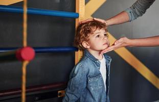 leraar meten kinderen hoogte binnenshuis in kleuterschool foto