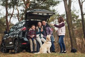 gelukkig familie hebben pret met hun hond in de buurt modern auto buitenshuis in Woud foto