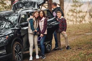 gelukkig familie hebben pret met hun hond in de buurt modern auto buitenshuis in Woud foto