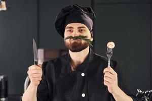 portret van professioneel jong chef koken in uniform dat poseren voor camera Aan de keuken foto