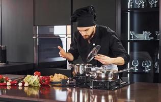 gebruik makend van apparatuur. professioneel jong chef koken in uniform werken Aan de keuken met groenten foto