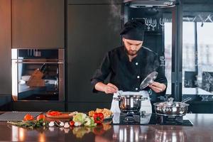 professioneel jong chef koken in uniform werken Aan de keuken foto