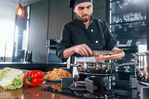 professioneel jong chef koken in uniform werken Aan de keuken foto