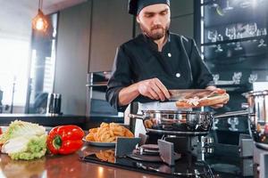 professioneel jong chef koken in uniform werken Aan de keuken foto