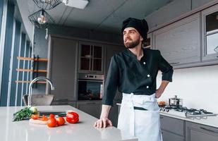 professioneel jong chef koken in uniform maken salade Aan de keuken foto