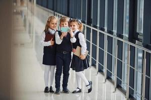 school- kinderen in uniform samen met telefoon en maken selfie in hal. opvatting van onderwijs foto