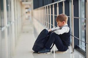 jongen in uniform zittend alleen met gevoel verdrietig Bij school. opvatting van Intimidatie foto