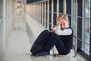 jongen in uniform zittend alleen met gevoel verdrietig Bij school. opvatting van Intimidatie foto