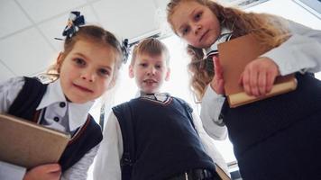 school- kinderen in uniform poseren voor een camera samen in hal. opvatting van onderwijs foto