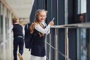 een weinig schooljongen steelt dingen van een meisjes zak terwijl ze is luisteren naar muziek- foto