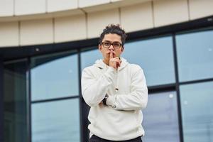 knap jong Mens met gekruld zwart haar- is Aan de straat tegen gebouw foto