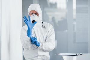 mannetje dokter wetenschapper in laboratorium jas, defensief eyewear en masker vervelend blauw handschoenen foto