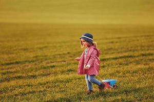 schattig weinig meisje wandelingen met speelgoed- auto Aan de mooi veld- Bij zonnig dag foto